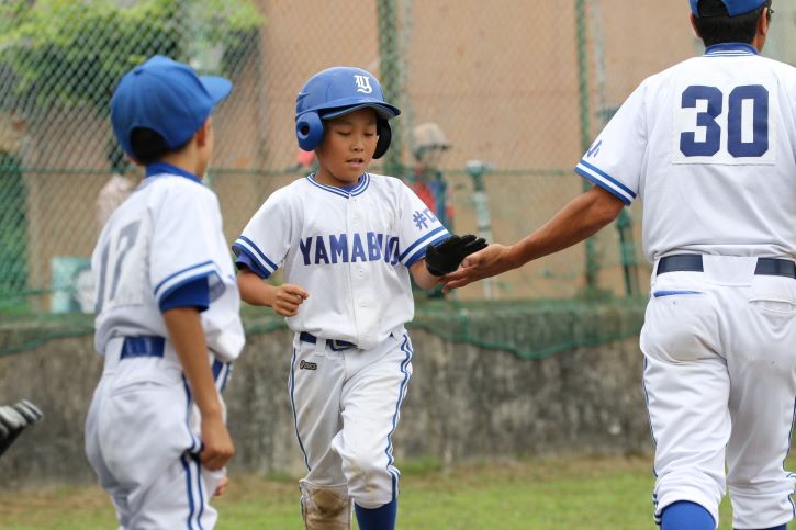 野球の試合で選手が監督と喜び合う様子